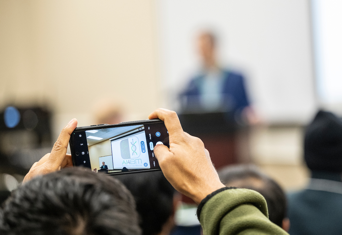 person holding a phone taking a picture of a screen presentation