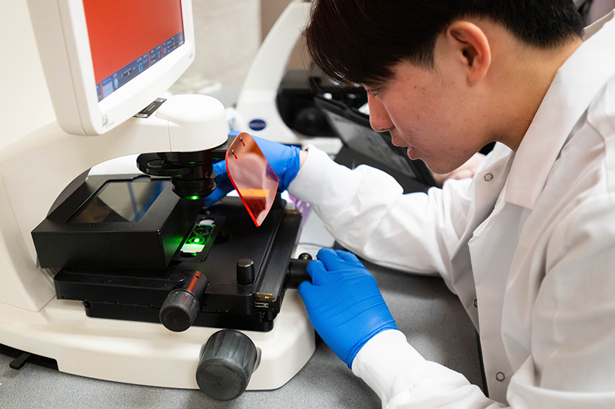 A S2 EMPWER participant looking through a microscope 