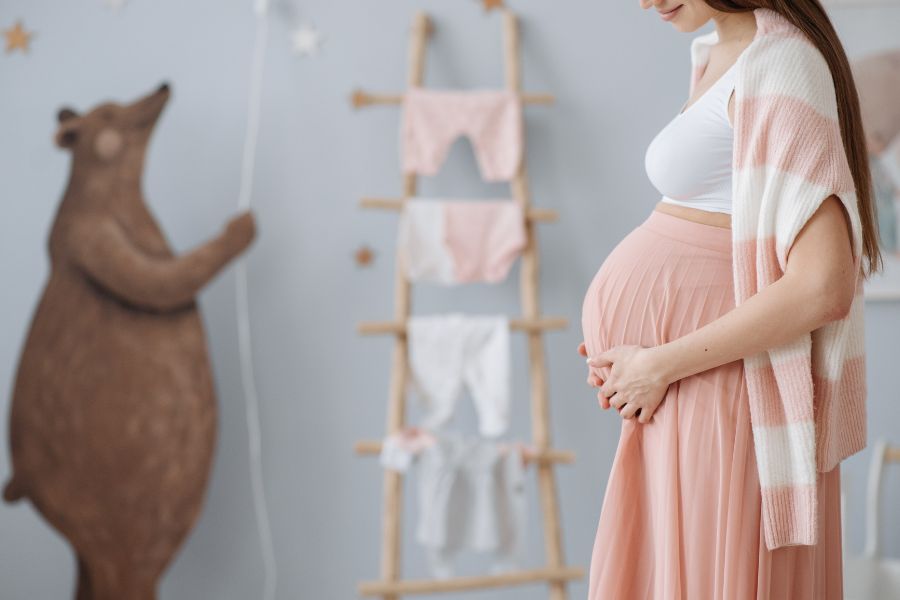 Stock photo of pregnant women holding belly in nursery