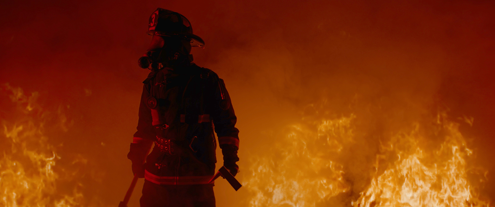 Firefighter stands in front of a blazing fire