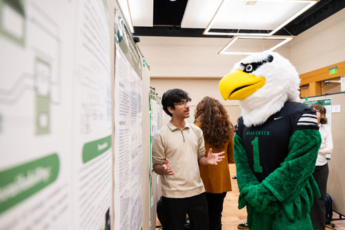 Mascot speaking to a student researcher.