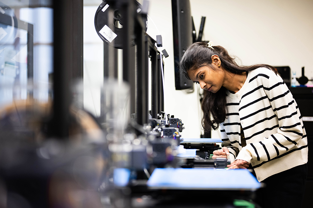 Photo of UNT student Seemaparevez Shaik working with a 3D printer.