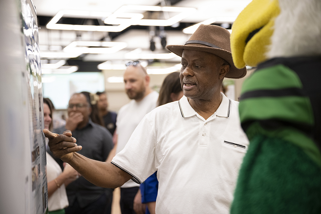 UNT student talking with UNT mascot Scrappy about research at University Research Day.