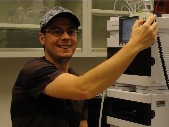 Photo of man (Jean Chrisophe Cocuron) smiling and working with a processor in a lab
