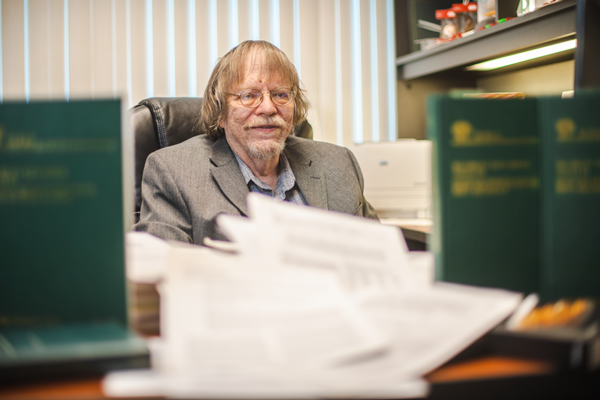 Bill Acree at his desk behind piles of papers