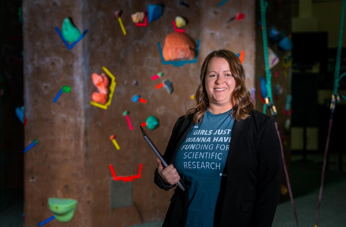 Photo of UNT educational psychology associate professor Melissa Savage in front of the climbing wall at the Pohl Recreation Center