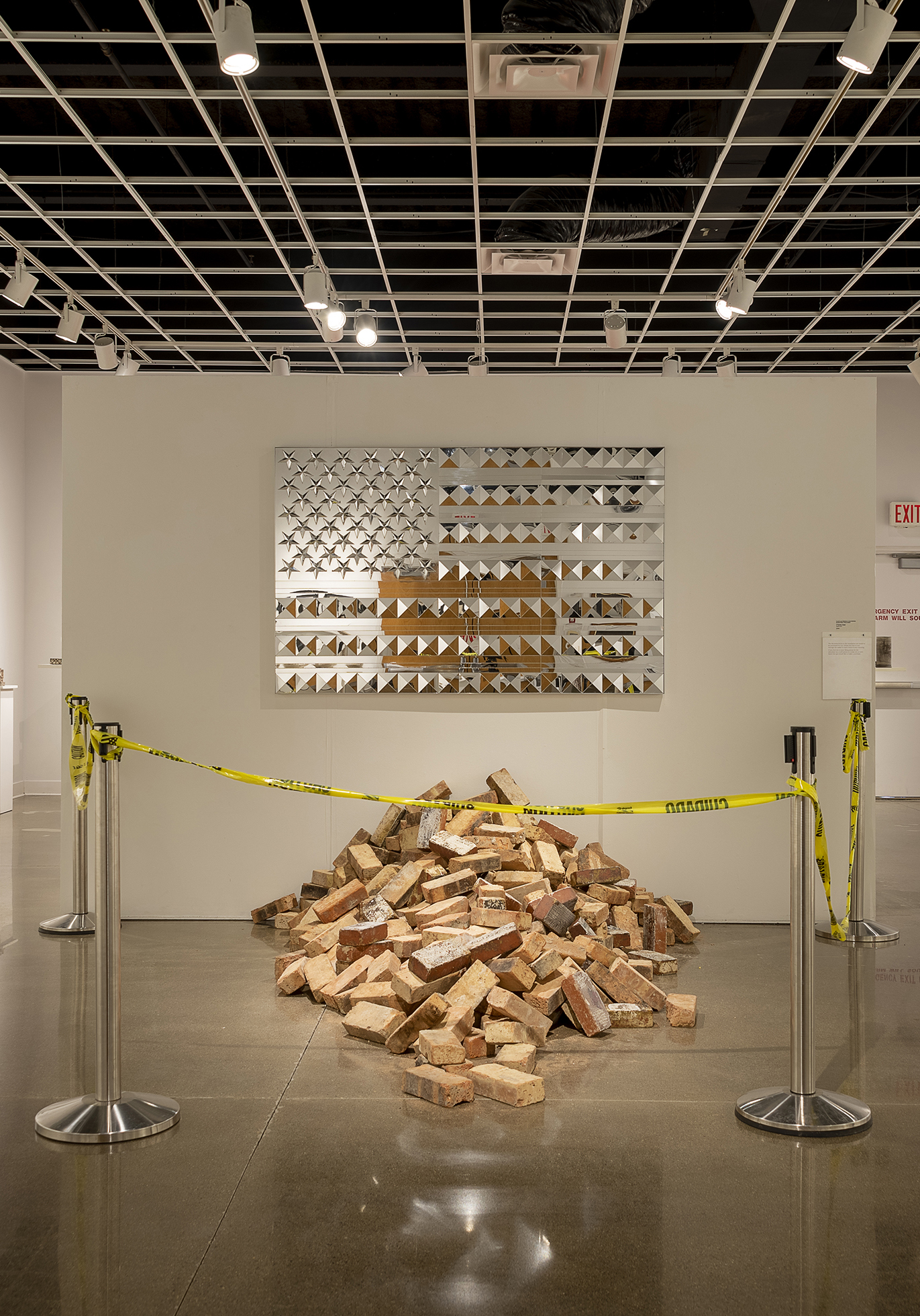 Photo of art gallery: pile of bricks with caution tape surrounding it.