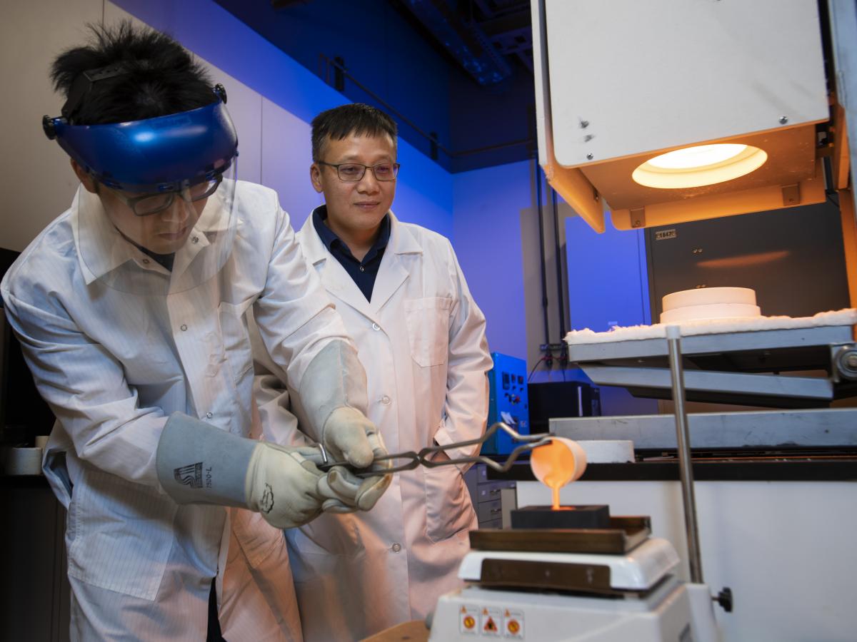 Ph.D. student Po-Hsuen Kuo pours molten glass as Professor Jincheng Du looks on.